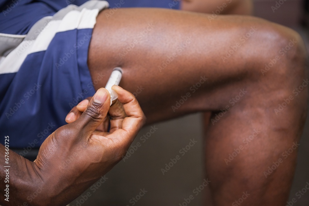 Muscular man injecting steroids