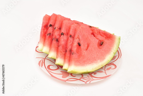 Cut pieces of watermelon on a plate on white background
