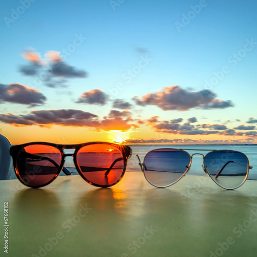 Fototapeta Naklejka Na Ścianę i Meble -  sunglasses on tropical beach table at sunset