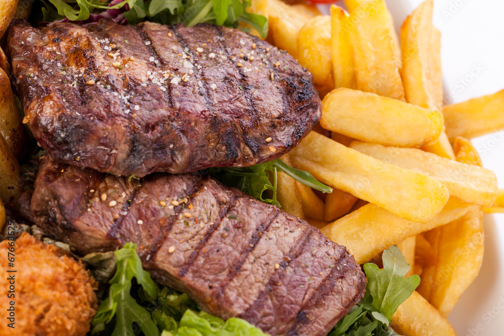 Platter of mixed meats, salad and French fries Platter of mixed meats, salad and French fries