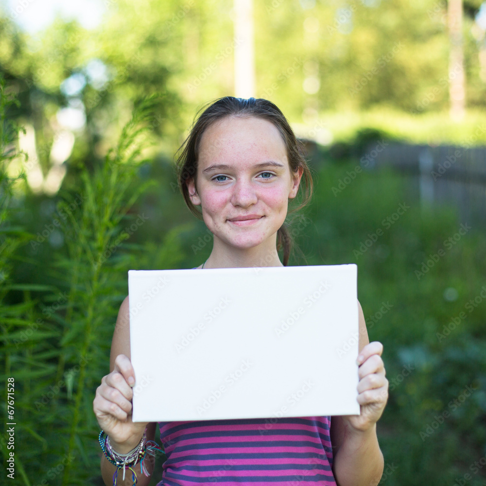 Cute teengirl holding clean white sheet paper, outdoors Cute teengirl holding clean white sheet paper, outdoors