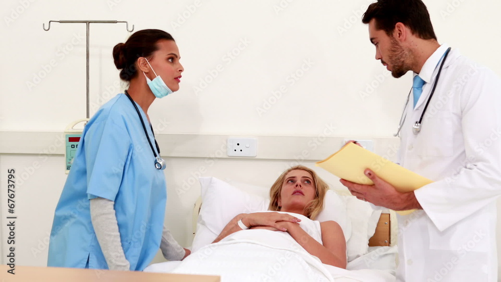 Medical team checking on sick patient in bed Medical team checking on sick patient in bed