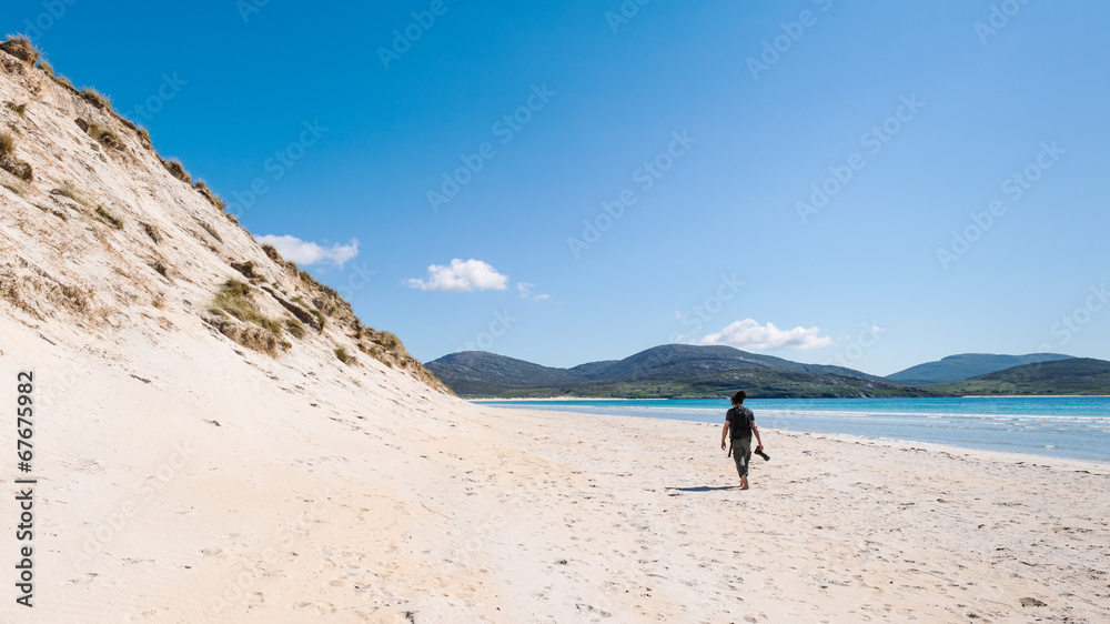 Photographer at a sunny white sand beach with high sand dunes