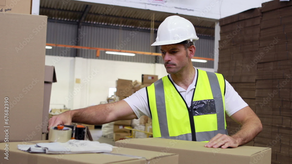 Warehouse worker sealing cardboard boxes for shipping