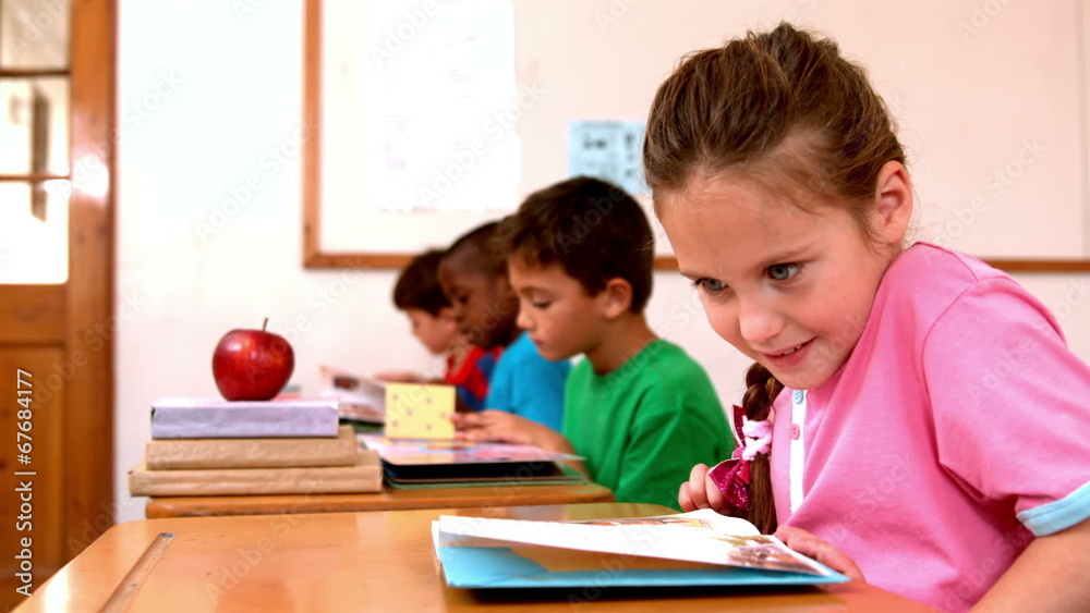 Cute little girl reading book in the classroom Cute little girl reading book in the classroom