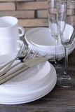 Set of white dishes on table on brick-wall background