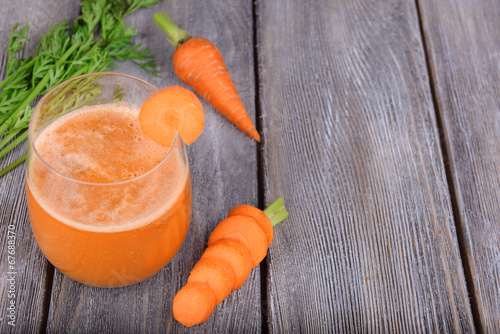 Glass of carrot juice and fresh carrots on wooden background