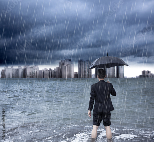 business man holding an umbrella and standing  with cloudburst