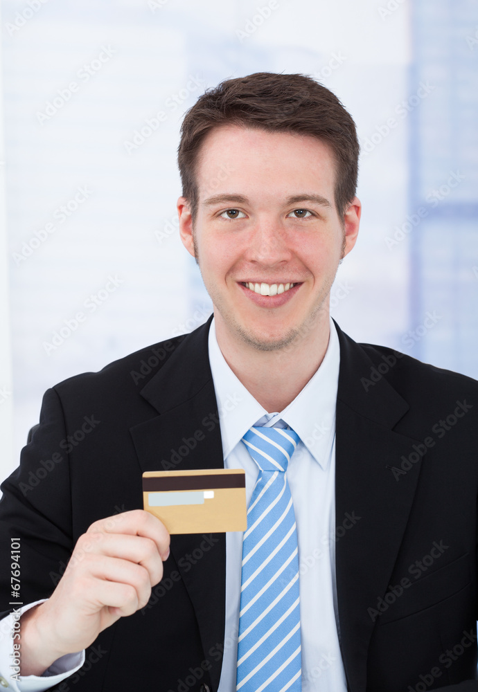 Confident Businessman Holding Credit Card In Office Confident Businessman Holding Credit Card In Office