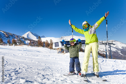 Mother and kid in masks standing with arms up