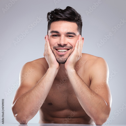 laughing young man holding his head in palms