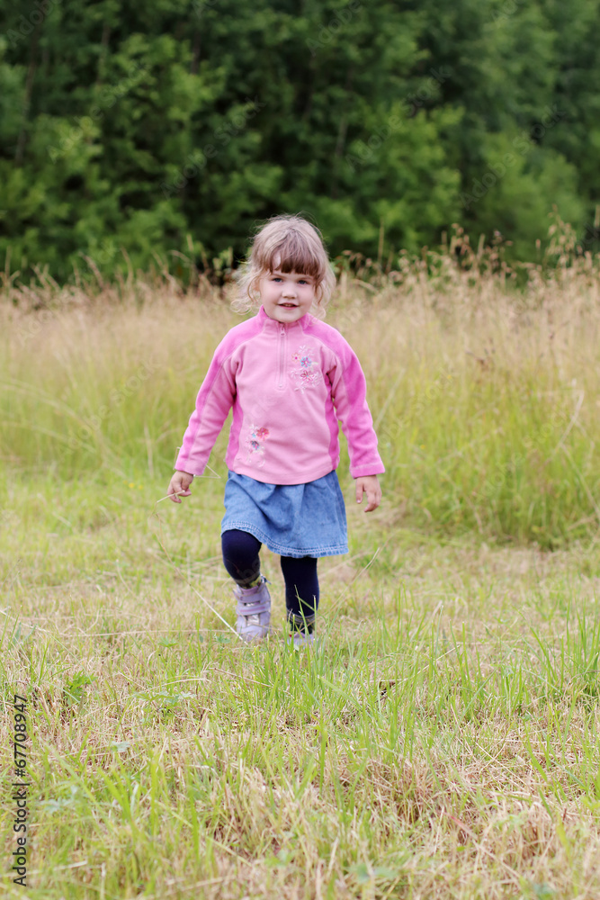 Little beautiful girl in skirt goes at green meadow in summer Little beautiful girl in skirt goes at green meadow in summer