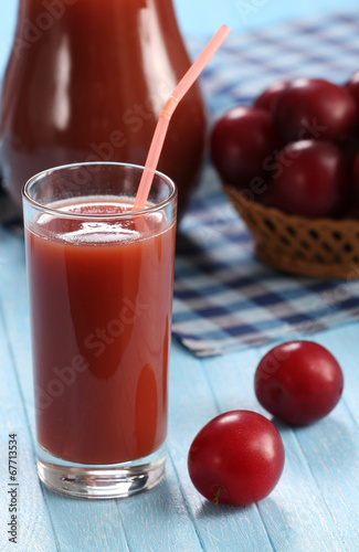 plum juice in a glass and pitcher, plums in a wicker basket