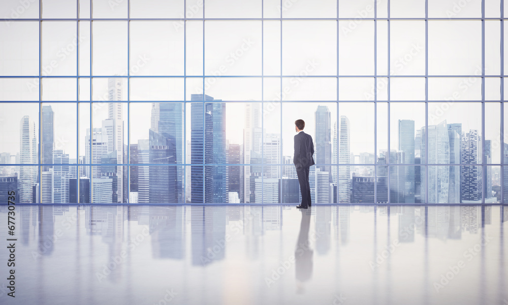 businessman standing in bright modern office with large windows