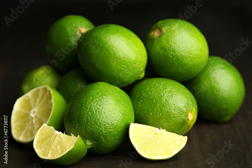 Fresh juicy limes on wooden table  on dark background