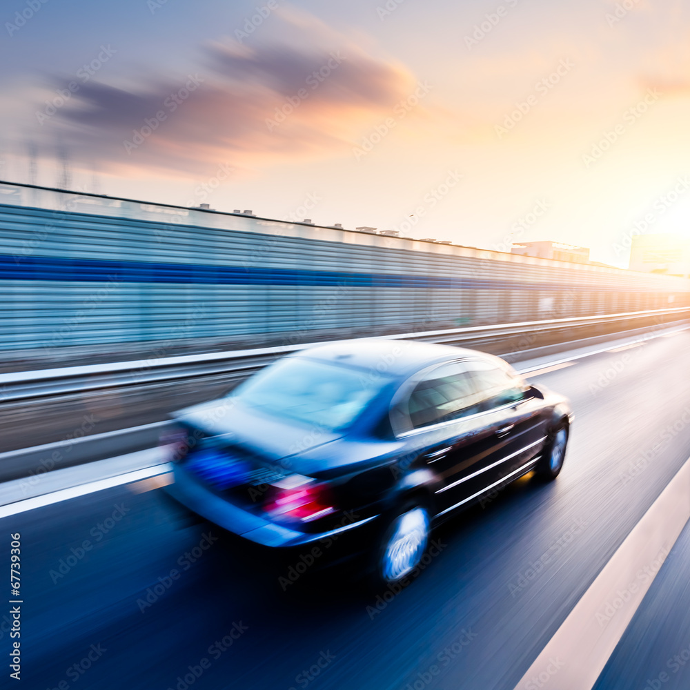 Naklejka premium Car driving on freeway at sunset, motion blur
