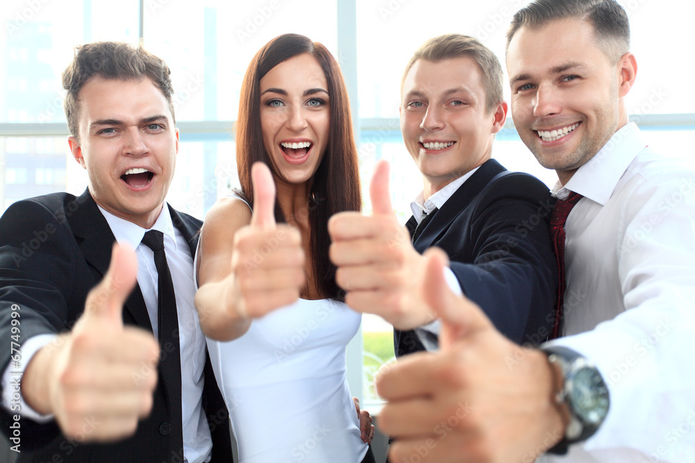 Successful young business people showing thumbs up sign Successful young business people showing thumbs up sign