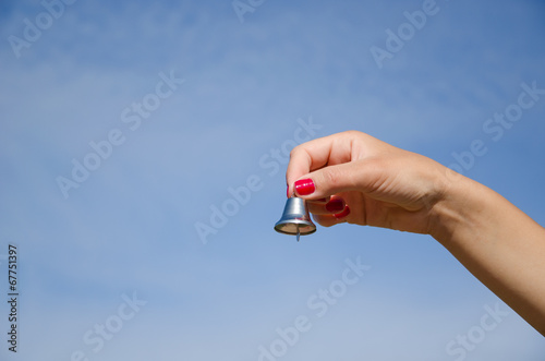 hand hold jingle silver bell on blue sky