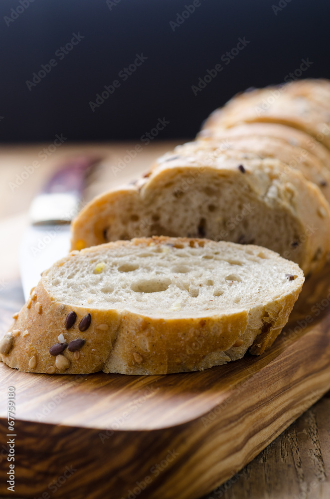 bread with seeds on a wooden board and knife