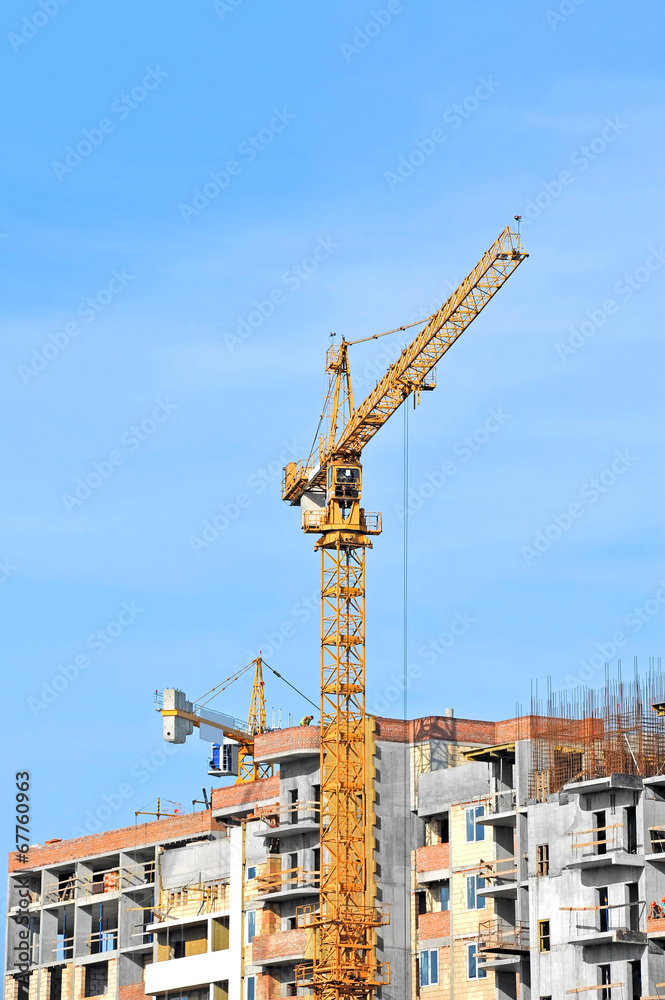 Crane and building construction site against blue sky Crane and building construction site against blue sky