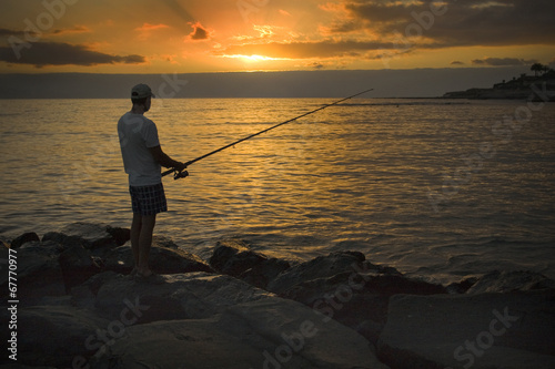Fisherman on the shore of the ocean at sunset