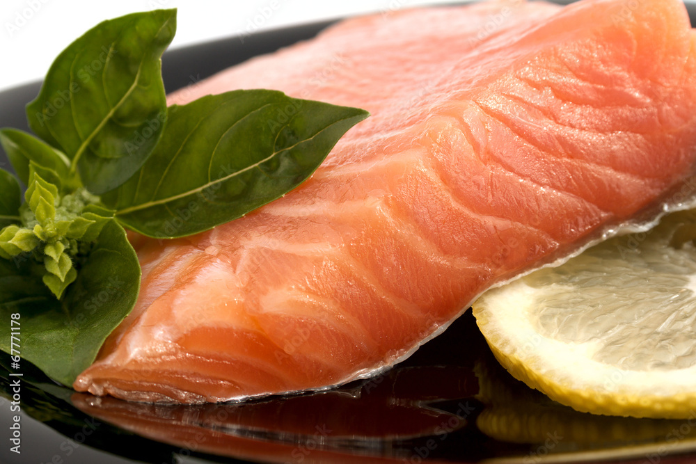 Salmon, basil and lemon on the black plate Salmon, basil and lemon on the black plate
