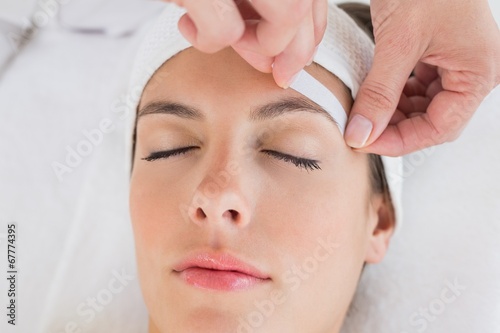 Hand waxing beautiful woman's eyebrow photo