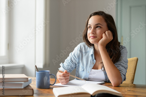Student teenage girl studying at home daydreaming photo