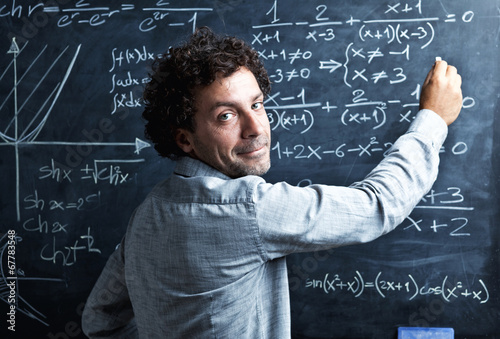  portrait of caucasian teacher with curly hair. slate blackboard on the background. school and teaching concept.