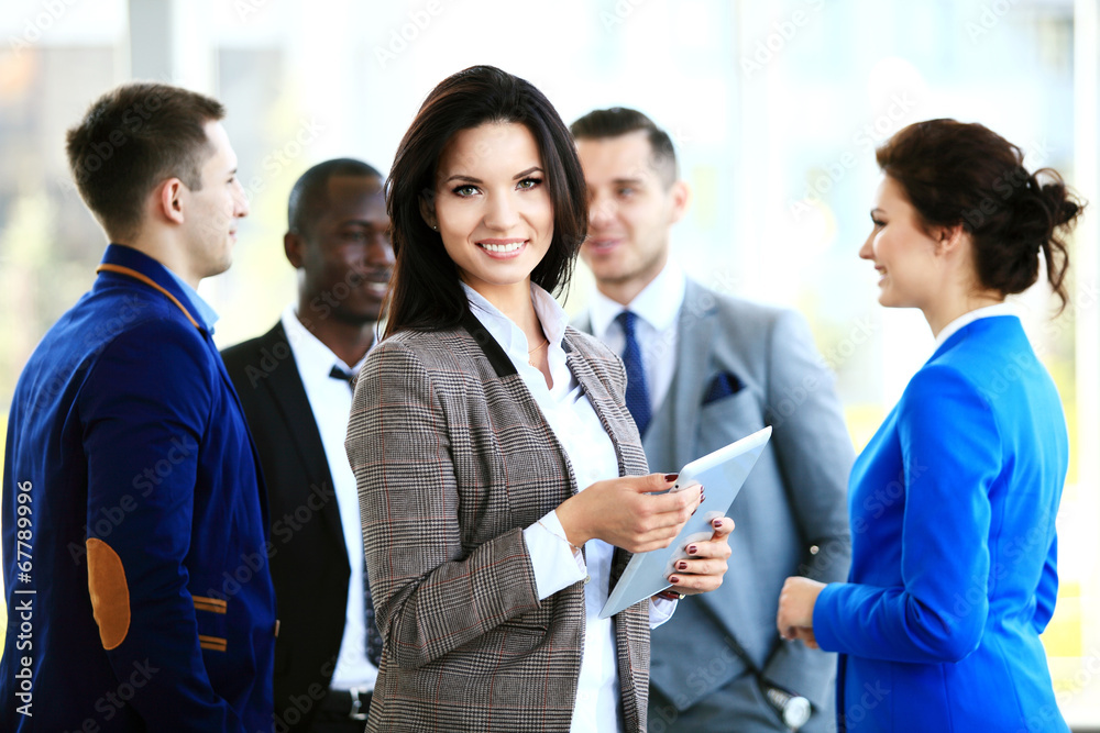 Business woman standing in foreground with a tablet in her hands