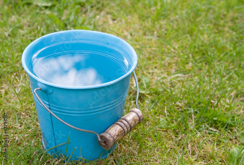 Blue bucket of water on grass