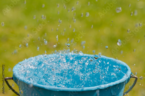 Rain falling into full bucket of water