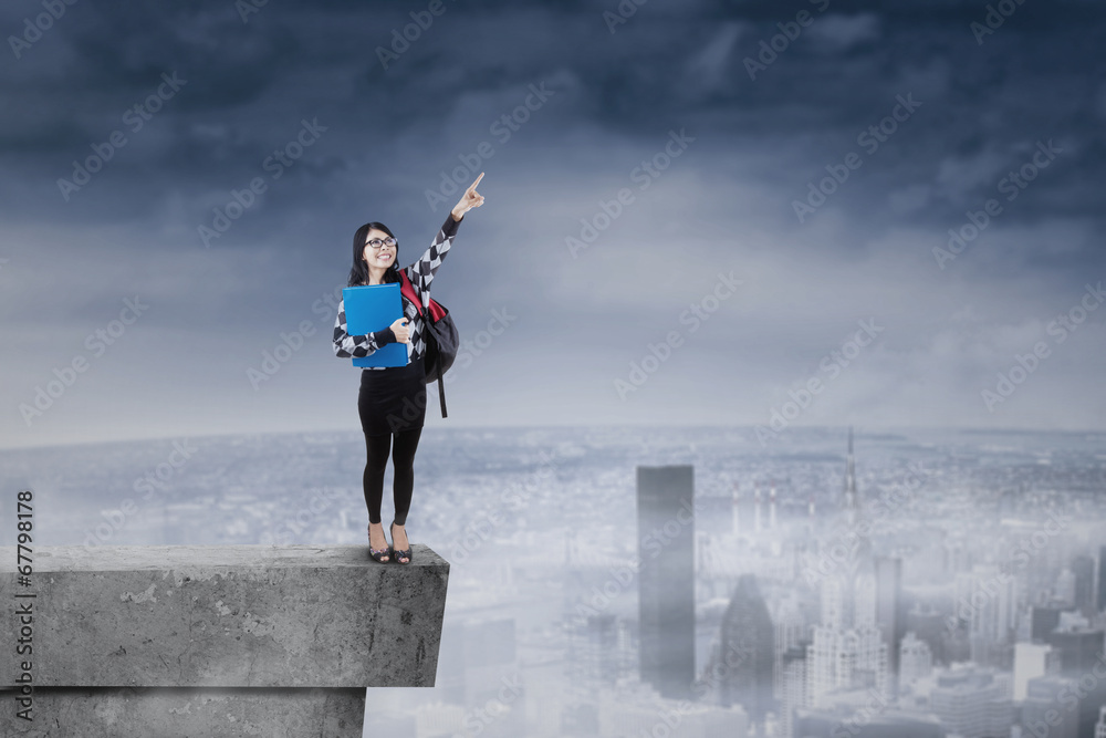 Student standing on rooftop and pointing at sky Student standing on rooftop and pointing at sky