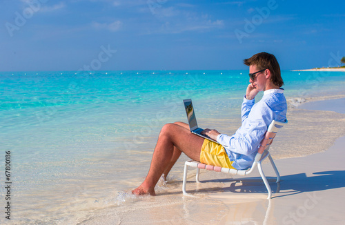 Young businessman using laptop on tropical beach © travnikovstudio