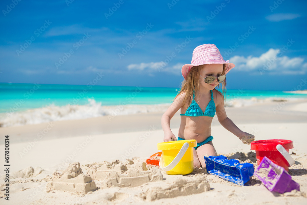Adorable little girl playing on the beach with white sand Adorable little girl playing on the beach with white sand