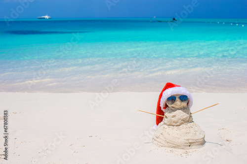 Little sandy snowman with red Santa Hat on white Caribbean beach