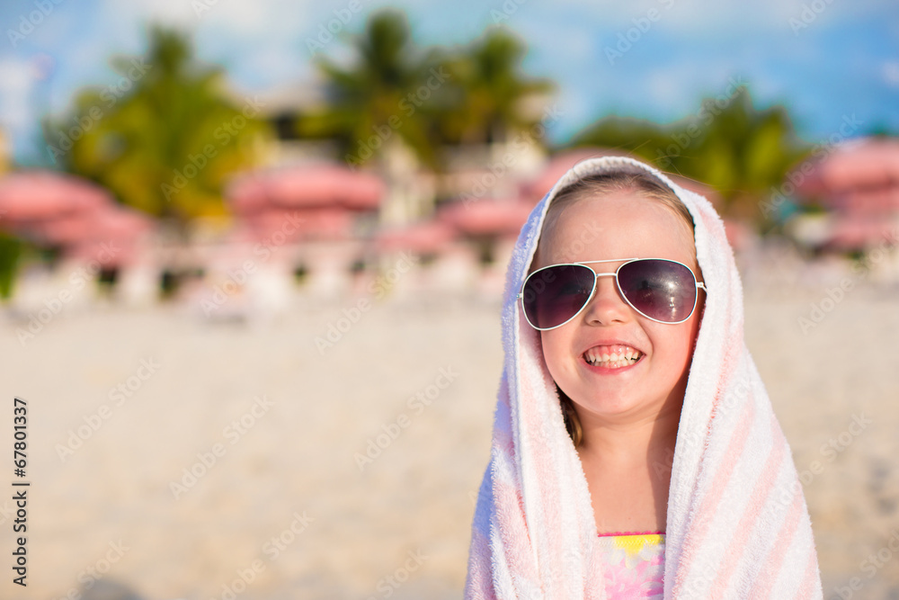 Adorable little girl in sunglasses covered with towel at