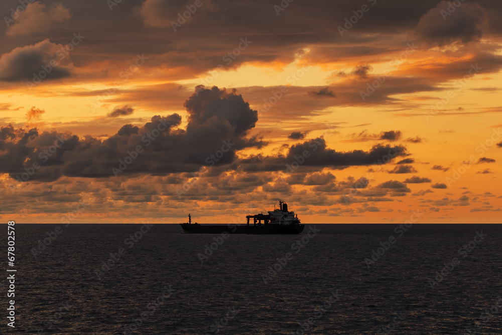 Cargo ship underway at sunset