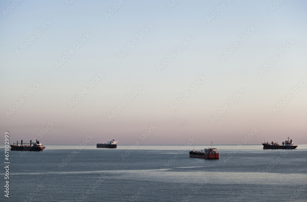 Four cargo ships at anchor on calm sea