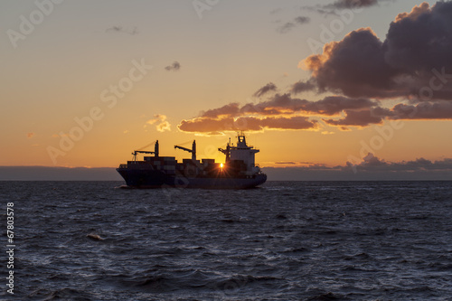 Cargo ship underway at sunset © Lukasz Z