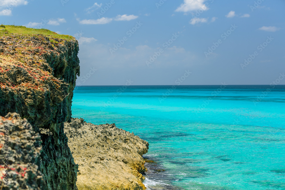 tropical background with tranquil ocean, cliff and blue sky