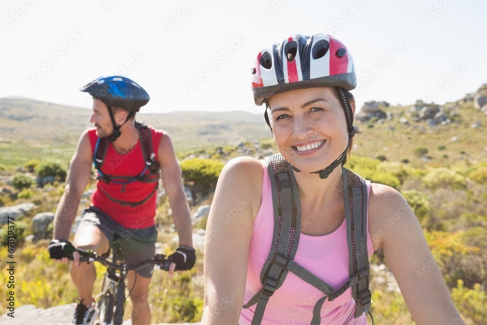 Fit cyclist couple smiling at camera on mountain trail