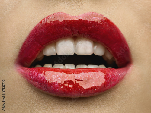 Close-up of woman's lips with bright fashion red glossy makeup.