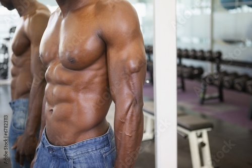 Mid section of a shirtless muscular man in gym