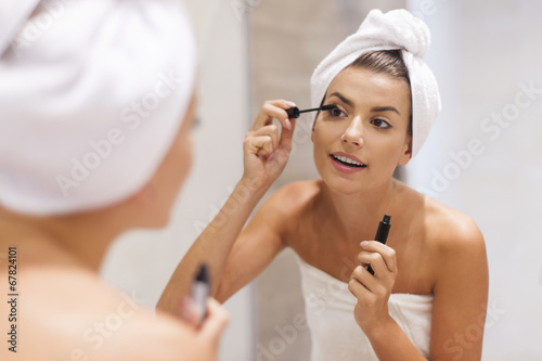 Beautiful woman using mascara in bathroom