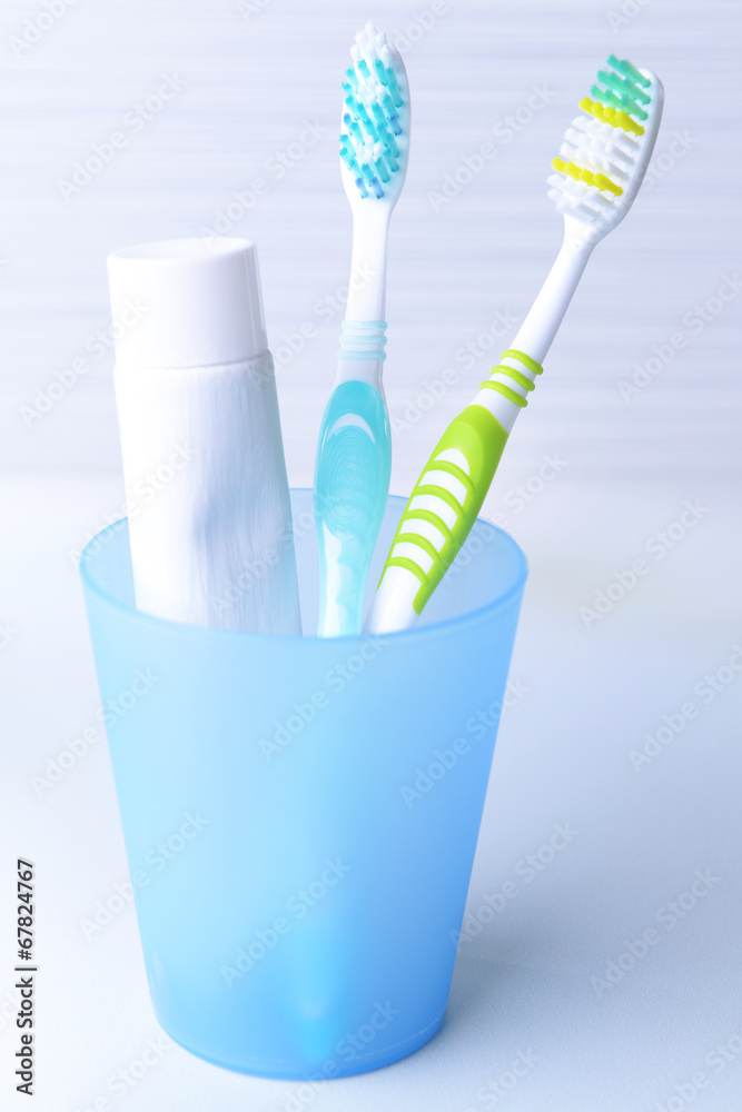 Toothbrushes in glass on table on light background Toothbrushes in glass on table on light background