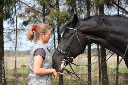 Young blonde woman and black horse smiling