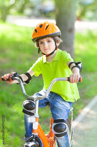 Child rides bike outdoors dressed in helmet