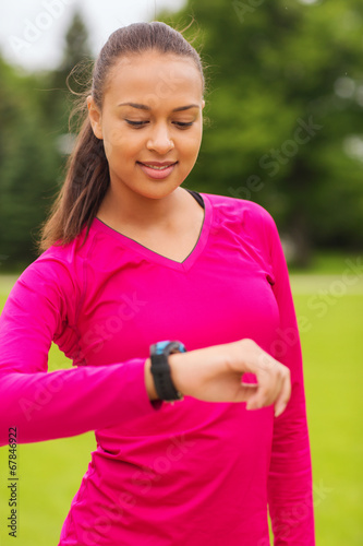 smiling young woman with heart rate watch