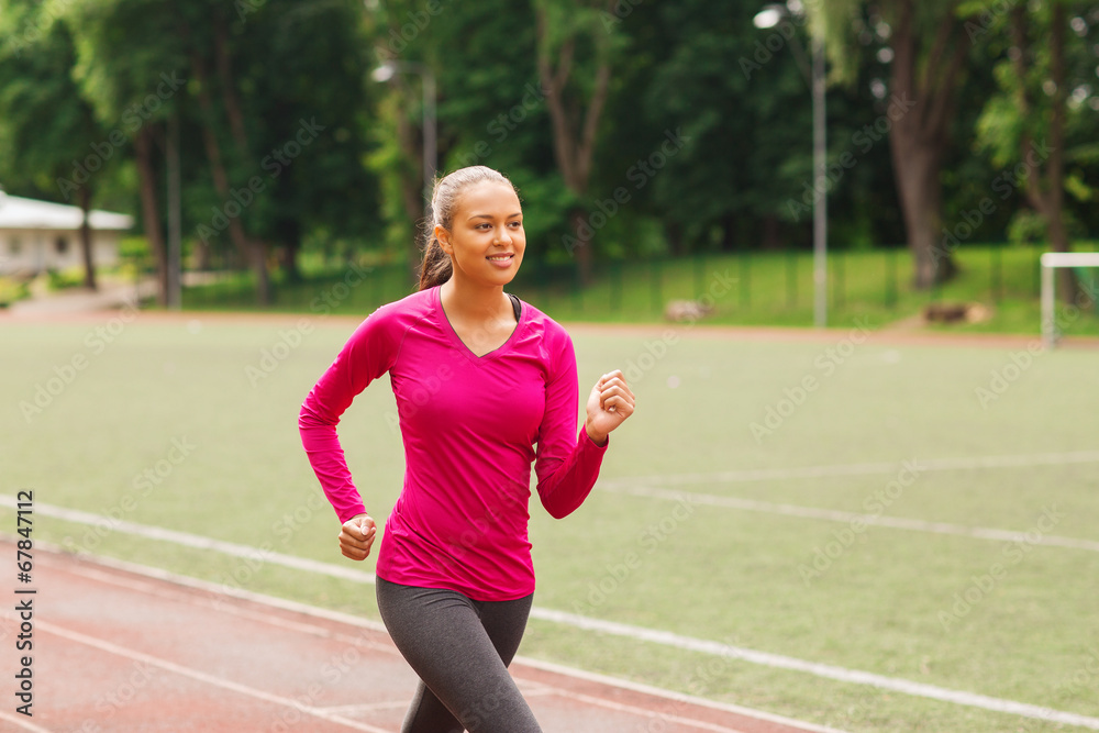 smiling woman running on track outdoors